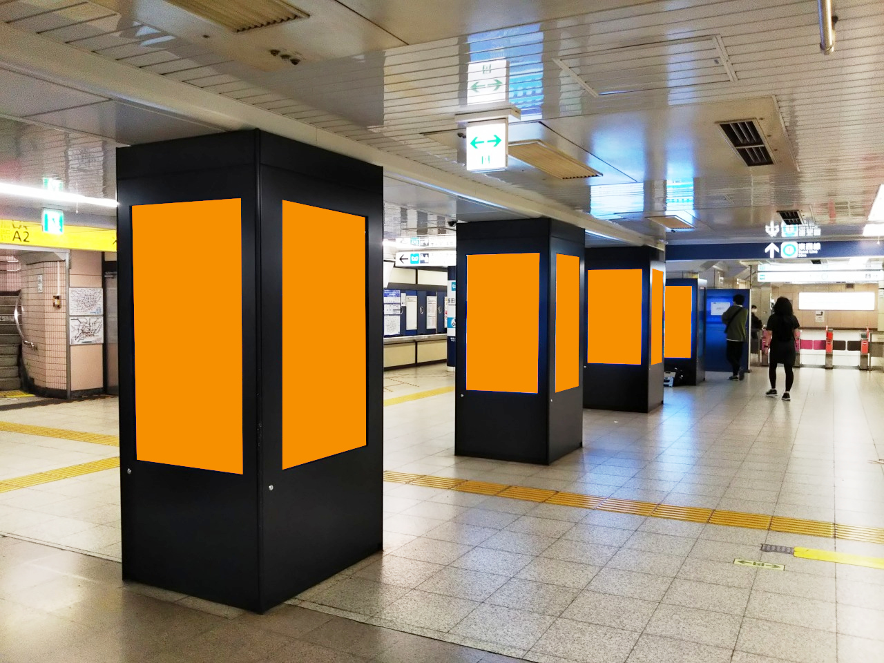 飯田橋駅の構内で展開する縦型のデジタルサイネージ広告の写真です